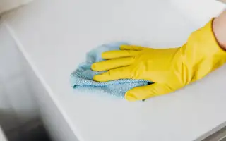 A gloved hand wiping down a clean stone countertop